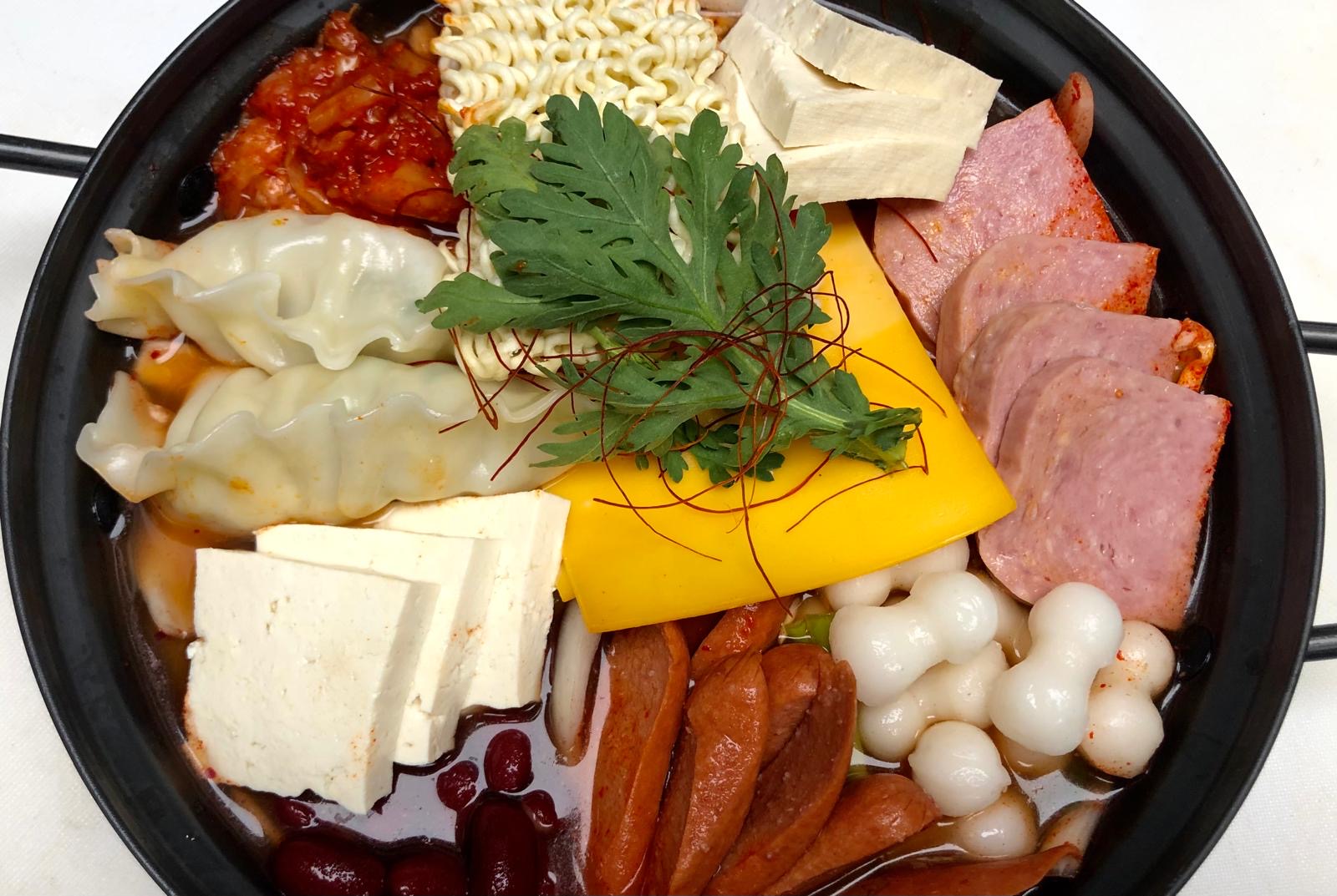 Assorted ingredients with noodles, vegetables, and meats on a white background.