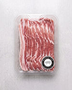 A plastic container filled with fresh, thinly sliced Berkshire pork belly strips showing distinct layers of red meat and white fat, labeled with a circular Berkshire Pork seal.