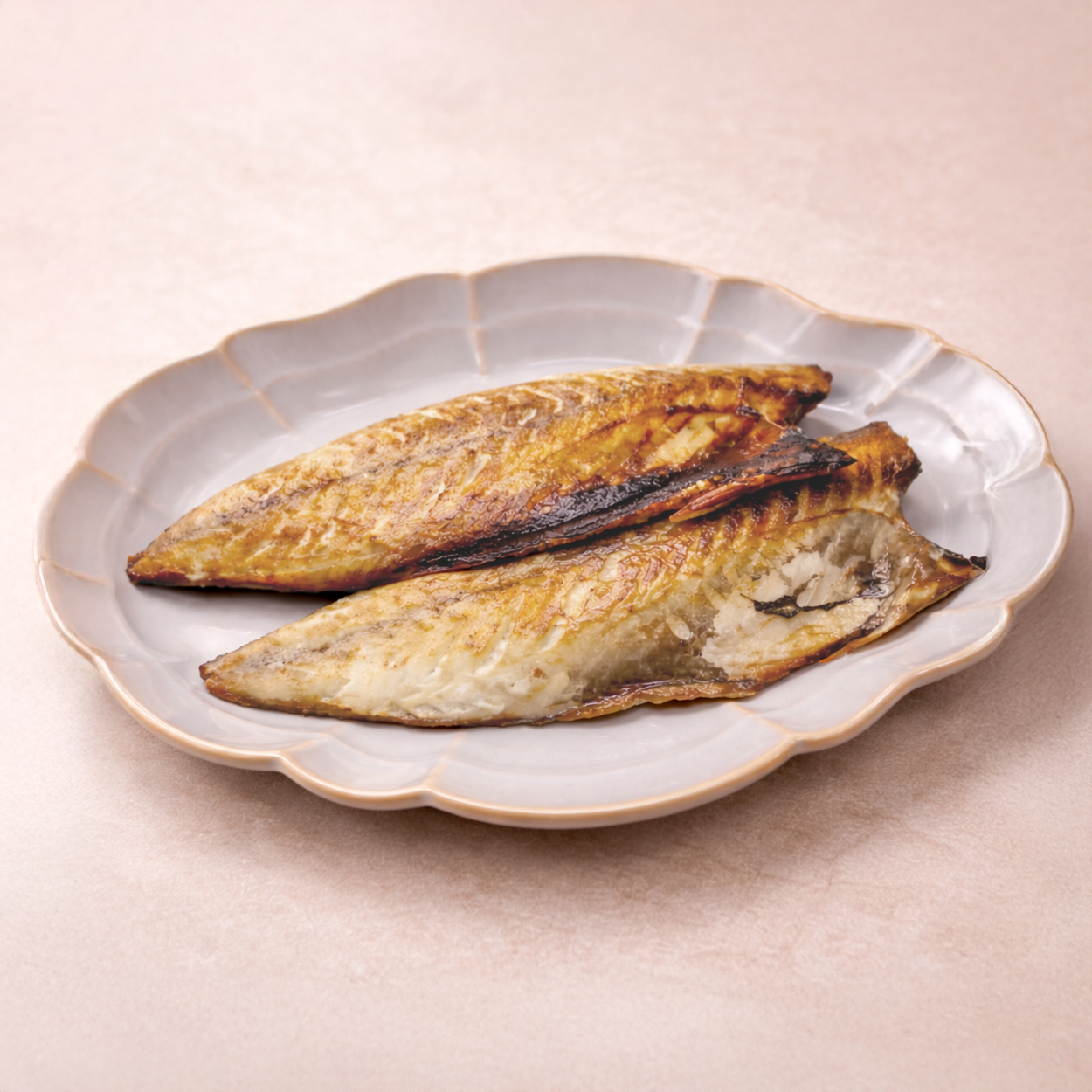 Two grilled fish fillets on a decorative plate with a beige background