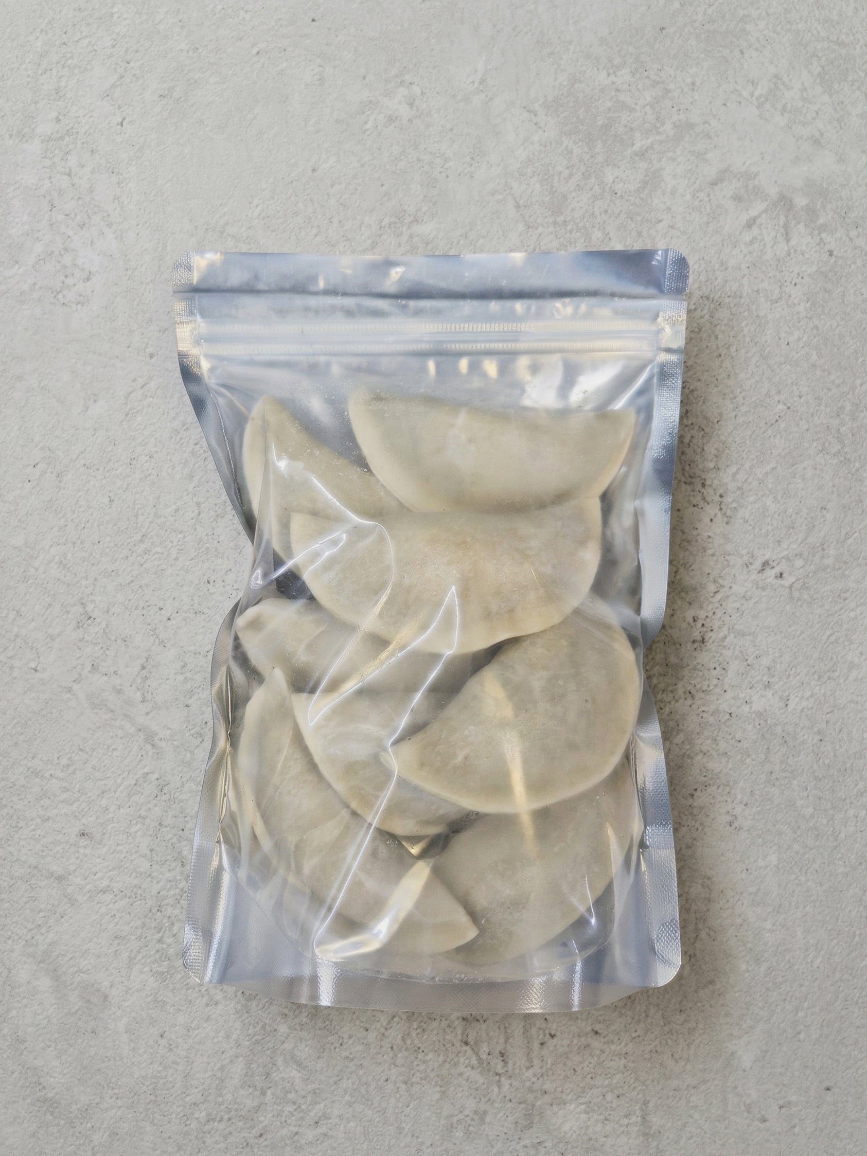 Packaged dumplings in a clear plastic bag on a gray surface