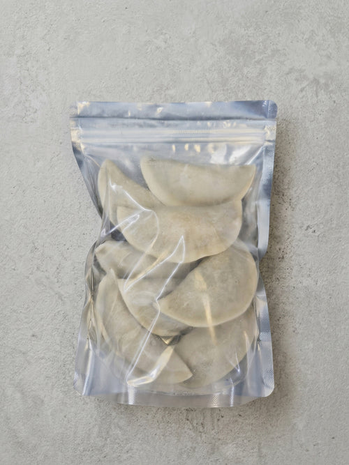 Packaged dumplings in a clear plastic bag on a gray surface